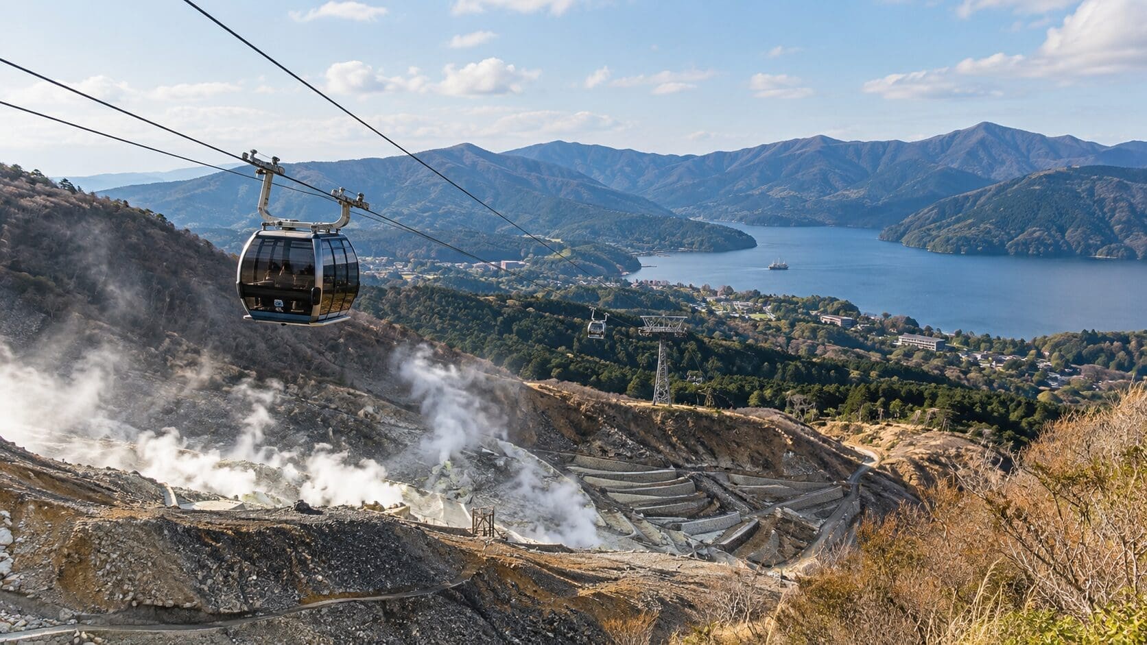 Hakone Ropeway gondola above a volcanic valley with Lake Ashi in the distance